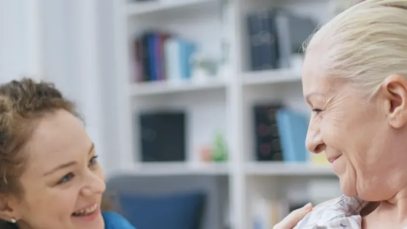 A carer sitting with an older woman at home.