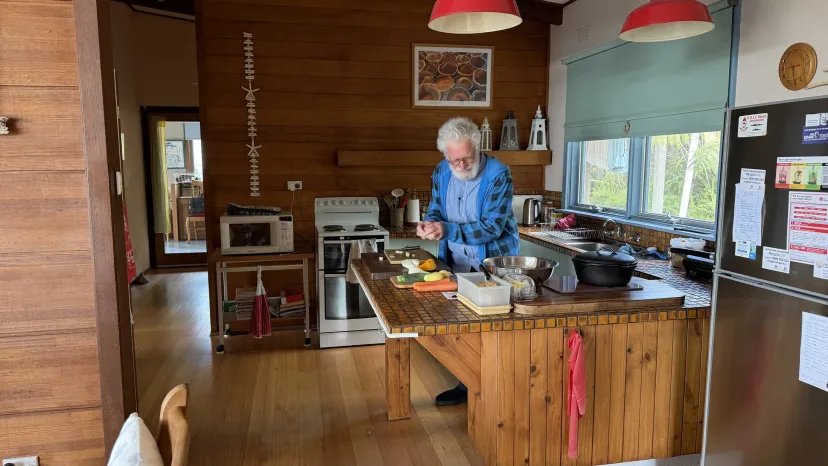 An older man cooking in the kitchen of his home.