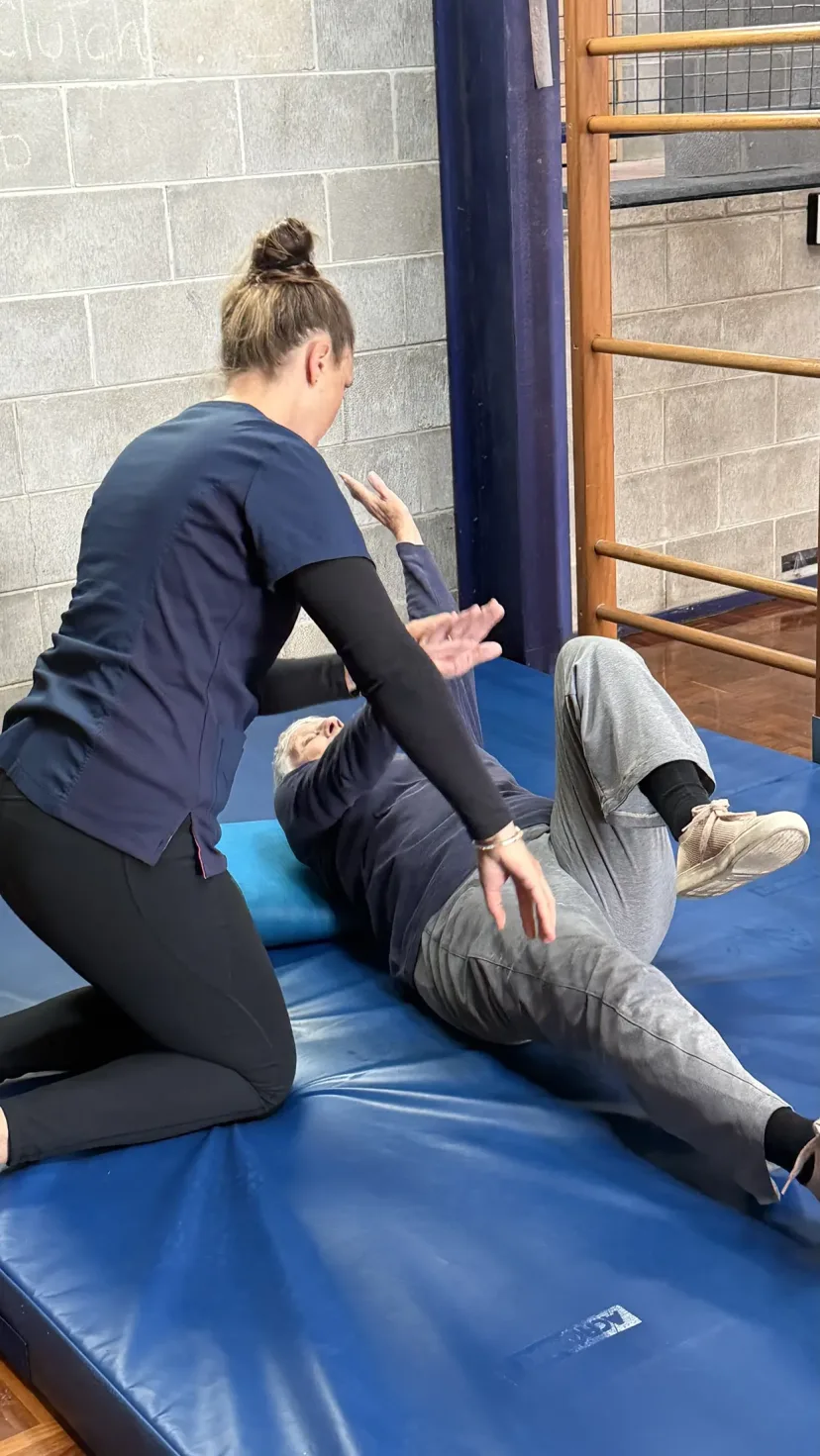 A physiotherapist working with a client on an exercise mat.