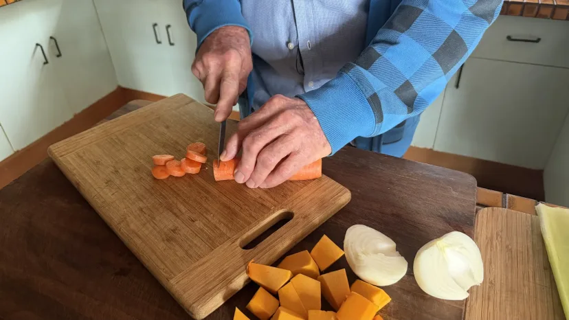 Pumpkin and onion being chopped on a kitchen board.