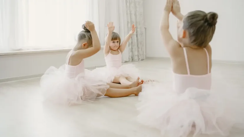 Young children in tutus dancing together in a bright studio.